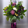 Bouquet of purple and white flowers in a purple vase with butterfly picks