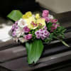 Pink and yellow floral arrangement with orchids and roses