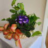 Basket of purple violets and green houseplants with a large ribbon bow