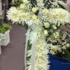 White floral cross with roses and ribbon on a stand