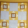 Yellow and white patchwork quilt with bee-patterned squares