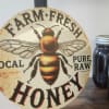 Round honey sign with a bee graphic beside a mason jar of honey
