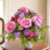 Pink roses and purple flowers arranged in a white vase