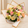 Pastel bouquet of roses, lilies, and small white filler flowers wrapped in white paper