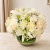 White lilies, roses, and mums arranged in a green glass vase
