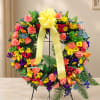 Colorful floral wreath on a stand with a yellow ribbon bow