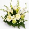 White roses and lilies arranged in a low basket with white filler flowers