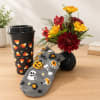 Fall bouquet in a black vase beside a Halloween coffee cup and patterned sock