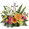 Floral arrangement with white lilies, pink roses, and orange gerbera daisies around a silver cross