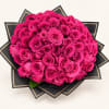 Bouquet of bright pink roses wrapped in black paper with gold trim