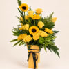 Yellow roses and sunflowers in a wrapped bouquet with a black ribbon