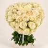 Heart-shaped bouquet of cream roses in a box with a lit "love" sign