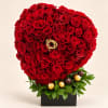 Heart-shaped red rose arrangement with chocolates in a black box