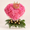 Pink floral heart arrangement topped with a gold crown and surrounded by chocolates