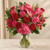 Pink lilies and red roses arranged in a clear glass vase