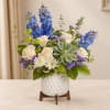 Blue and white floral arrangement in a white vase with a succulent centerpiece