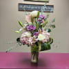 Tall bouquet of roses, lilies, and hydrangeas in a glass vase