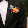 Boutonniere with peach and blue flowers on a black suit jacket