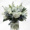 White floral bouquet in a clear glass vase with a sheer ribbon