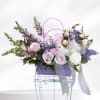 Lavender and white floral arrangement in a purple handled basket