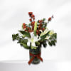White lilies and red berry branches in a glass vase with a red ribbon