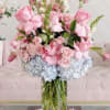 Pink roses and pale blue hydrangeas in a clear glass vase