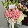 Pink roses and pale hydrangeas in a glass vase with a ribbon