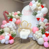 Balloon arch with a chair and "Santa Baby" sign
