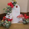 Balloon display with ladybug and mushroom decorations for a baby announcement