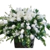 White floral arrangement in a dark vase with trailing greenery
