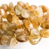 Pile of polished amber-colored stones on a white surface