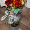 Floral arrangement in a metal milk can with plaid ribbon and a decorative sign