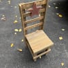 Wooden chair with a star cutout on the backrest, sitting on pavement with scattered leaves.