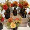 Small autumn floral arrangements in amber glass bottles