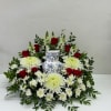Red roses and white chrysanthemums arranged around a blue-and-white vase