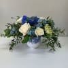 White roses and blue flowers arranged in a blue-and-white vase
