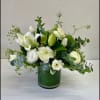 White flowers arranged in a green vase with airy greenery