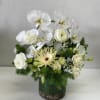 White orchids and pale blooms arranged in a green vase.