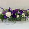 Purple and white floral arrangement in a low rectangular container