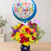 Birthday balloon above a colorful flower arrangement in a vase