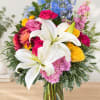 Colorful bouquet with white lilies, roses, and blue flowers in a glass vase