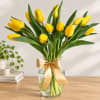 Yellow tulips in a clear glass vase with a gold ribbon