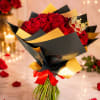 Bouquet of red roses wrapped in black and gold paper with a red ribbon
