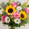 Bouquet of pink roses, sunflowers, and white daisies in a glass vase