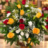 Mixed bouquet of red and yellow roses with white filler flowers in a wooden basket