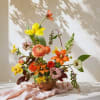 Colorful mixed floral arrangement in a round vase with orange, yellow, and pink blooms