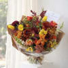 Bouquet of mixed orange, yellow, and burgundy flowers wrapped in brown paper