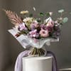 Pink and lavender bouquet with roses and mixed blooms wrapped in white paper
