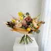 Mixed bouquet of cream, pink, and yellow flowers wrapped in tan paper