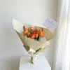 Bouquet of orange and pink ranunculus wrapped in cream paper